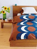 Retro bedspread and sunflowers in vase on side table