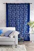 Blue and white printed wall hanging behind white sofa in living room