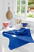A blue knitted cloth on a kitchen table in front of a window