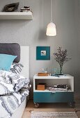 Pendelleuchte über rollbarem Nachttisch neben dem Bett im Schlafzimmer mit grau getönter Wand