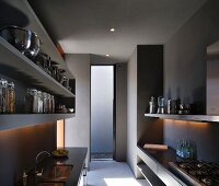 Grey, minimalist kitchen with integrated sink, gas hob and plain shelving with stainless steel and glass vessels