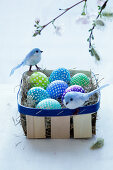 Easter eggs and decorative birds in a wooden basket