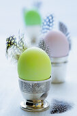 Coloured eggs and feathers in egg cups