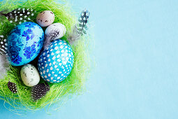 Eggs and feathers in a green Easter nest