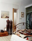 Vintage mannequins beside an open door and antique metal bed stead