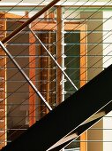 Ausschnitt einer Treppe aus Metall mit Geländer und horizontalen Drahtseilen