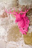 A pink stag decoration on a stone wall