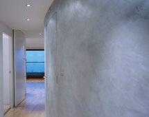 Gray curved wall in a hallway with open door and view of a window