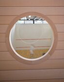 View through a bull's eye in a wooden facade into a squash court