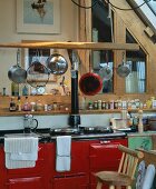 Vintage kitchen counter with red lacquered cabinets and hanging pots and pans