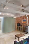 Renovierter Wohnraum mit Ziegelwand und weiss lackierter Holzdecke darunter moderner hufeisenförmiger Einbau