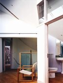 Wood frame chair and sailcloth in front of a wall with a view through an open bathroom door of the toilet