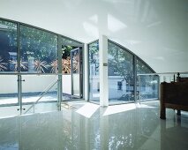 Modern living room under a barrel roof with reflective tiled floor in front of bank of windows