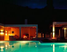 Evening mood at the pool with underwater lighting and fire in the fireplace on a terrace