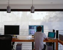 Arbeiten am Computer im modernen Büro mit weissen Flächenvorhängen am Fenster