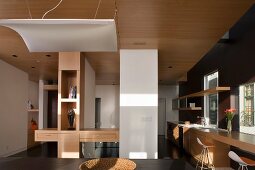 Zeitgenössischer offener Wohnraum mit Esstheke und Lichtsegel unter Holzdecke