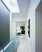 White stairwell with skylight and view into an open passage into the living room of a contemporary home