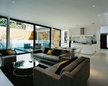 Graue Sofagarnitur im offenen Wohnraum mit Küche vor Terrassenfenster