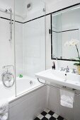 Ein weisses Badezimmer mit Badewanne und schwarz-weissen Bodenfliesen
