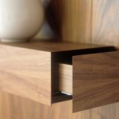 A wood panelled shelf with an open drawer