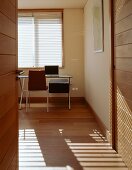 A view through an open door onto a modern desk and chair in a simple room
