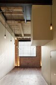 Englisches Loft mit Industrieverglasung in Backsteinwand und sich kubisch durchdringenden, weissen Raumeinbauten