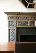 Detail of elegant, classical mantelpiece behind a fine wood table