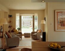 Graue Sessel mit Zierkissen und Stehlampen im skandinavischen Stil in offenem Wohn-/Essbereich mit grossflächiger Fensterfront