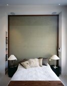 French bed and modern bedside lamps with metal bases in front of wood-framed exposed concrete wall