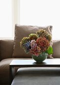 A sofa and table combination and a vase of hortensias