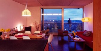 Offener moderner Wohnraum mit Essplatz und raumhohen Terrassenfenstern mit Abendstimmung