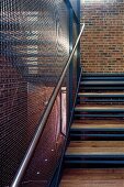 Wood and metal stairway with transparent wire mesh wall in a factory