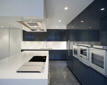 Coole Designerküche mit weißem Küchenblock vor schwarzem hochglänzenden Einbauschrank
