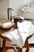 Rustic, old wooden stool with modern bathroom utensils and antique silver box