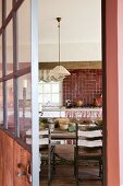 View through open door into rustic kitchen with dining area and dusky pink accents
