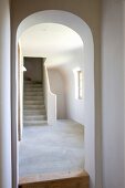 View through arched doorway of stone stairs in simple stairwell