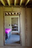 Zimmerflucht eines Fachwerkhauses durch das Schlafzimmer mit Tagesbettdecke in Magenta, in ein Bad ensuite