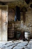 Rustic shed with stone floor and old wooden barrels against wall