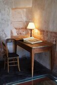 Table lamp on wooden table against wall with faded stencilled pattern