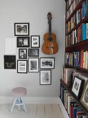 Black and white photographs and guitar on wall next to bookcase