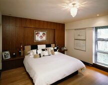 Modernes Schlafzimmer mit Doppelbett vor Holzverkleidung