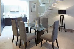 Dining table with chairs and standard lamp under stairs in open-plan living space