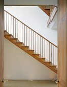 Blick durch offene Tür auf Holztreppe im modernen Treppenhaus