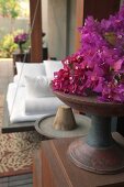Bougainvillea flowers in wooden dish on wooden cabinet in front of spa swing bed
