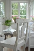 White kitchen chair next to bench and rustic side table in loggia