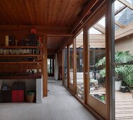 Wohnraum mit Holzverkleidung an Wand und Decke und Blick durch offene Schiebetür in angrenzenden Raum