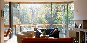 Hillside solar house - seating area in front of fireplace with view of treetops