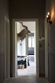 Stimmungsvolle Wandbeleuchtung im Flur und Blick durch offene Tür auf Tiertrophäe an Wand