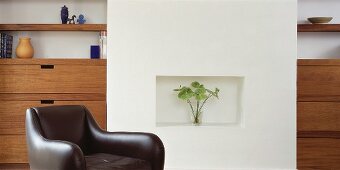Armchair in front of wall with niche and fitted shelves