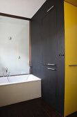 Bathtub, black fitted cupboard & yellow niche